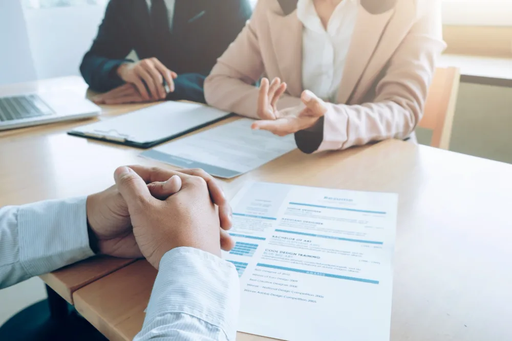 Twee mensen voeren een gesprek aan tafel met een cv en documenten voor zich